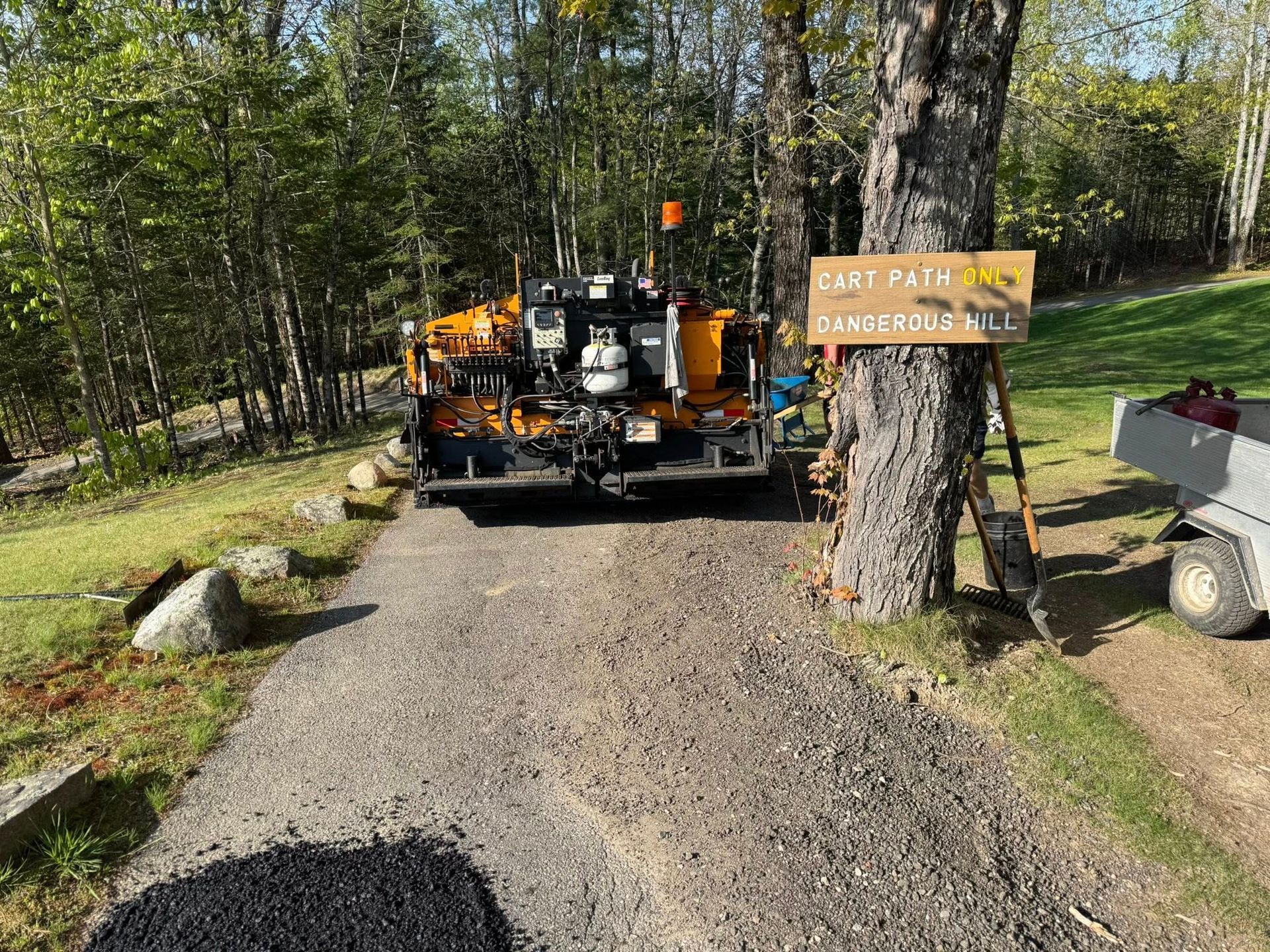 A truck is driving down a dirt road next to a tree.