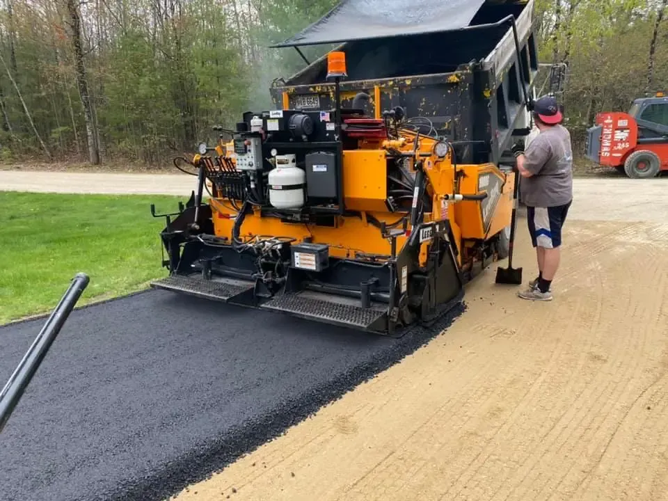 A man is standing on the side of a dirt road.