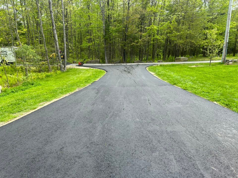 A road that is going through a lush green field.