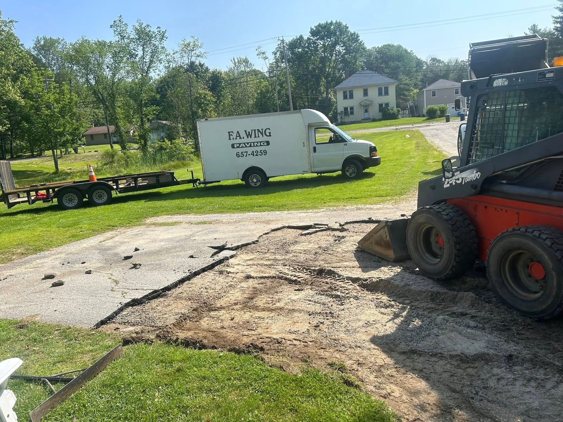 A white van is parked on the side of the road next to a bulldozer.