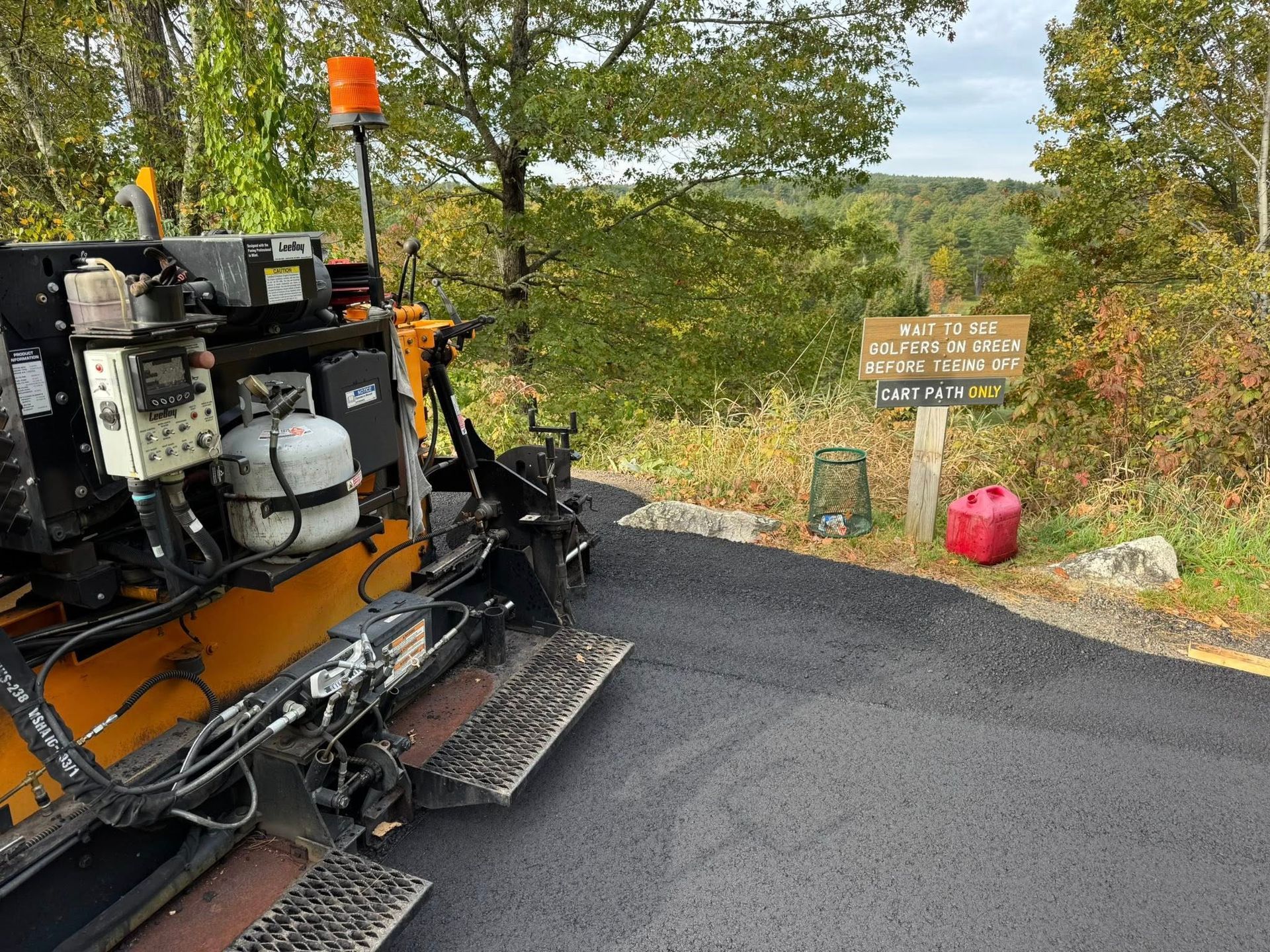 A large building is being built next to a large asphalt driveway.