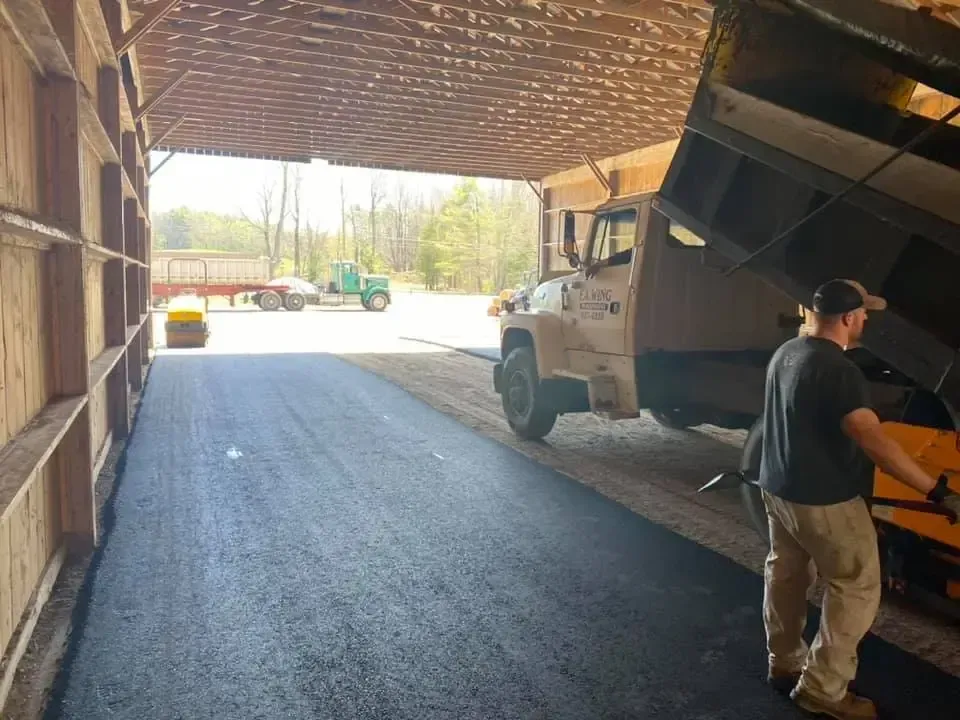A man is standing next to a dump truck in a garage.