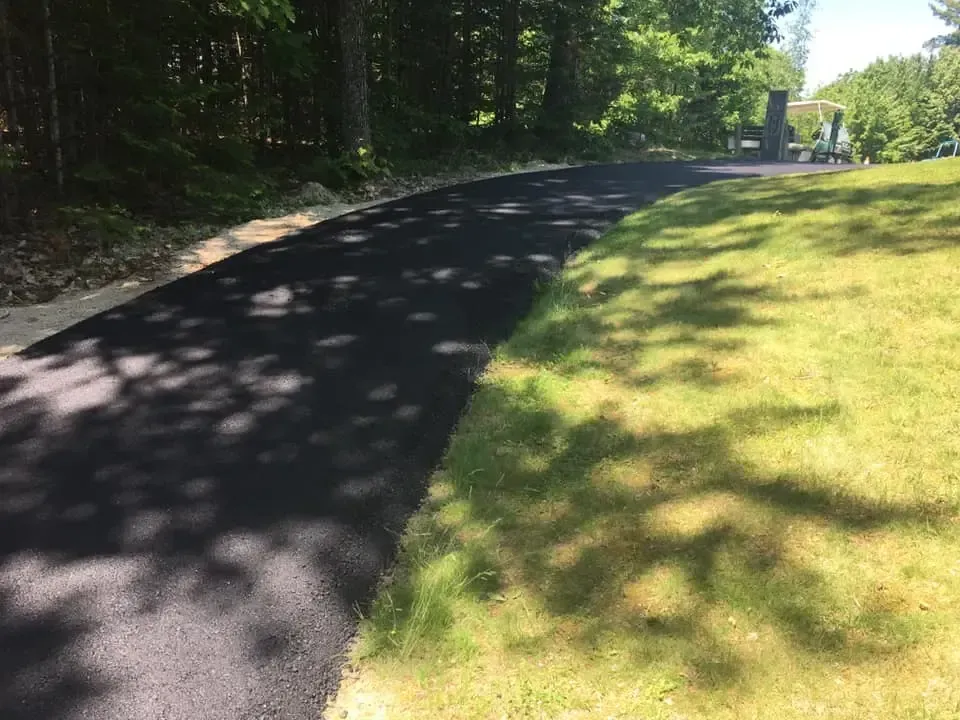 A black asphalt road going through a grassy field.