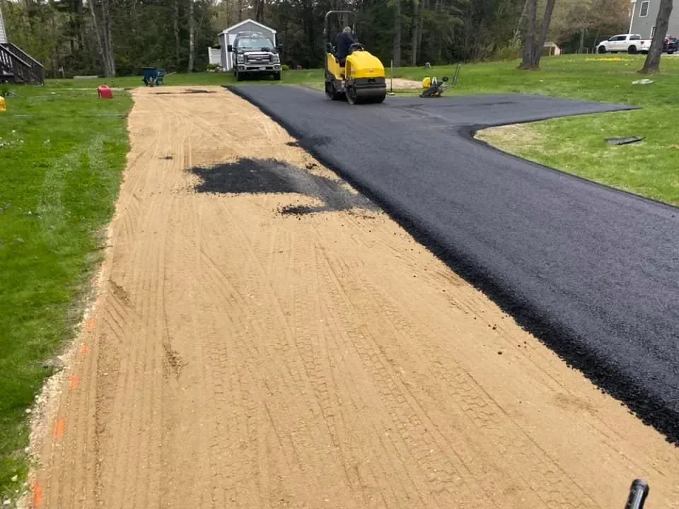 A man is driving a roller on a dirt road.