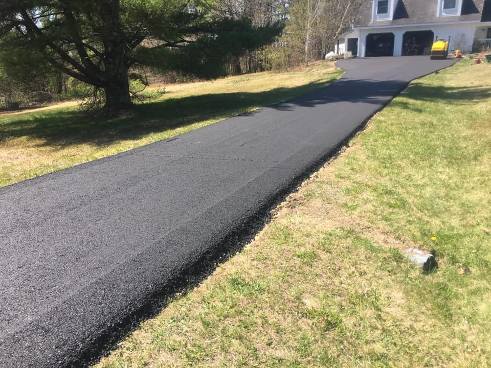 A black asphalt driveway leading to a house.