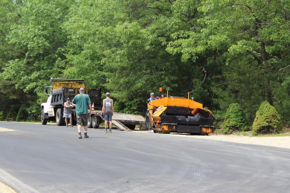 A group of people are walking down a road next to a truck.