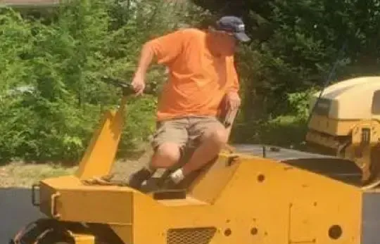 A man is riding a yellow roller on a road.