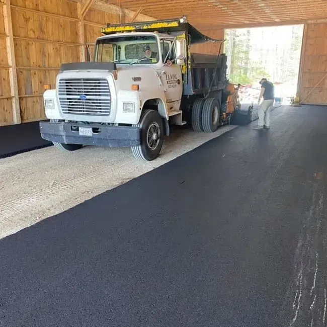 A dump truck is parked in a garage with a man standing next to it.