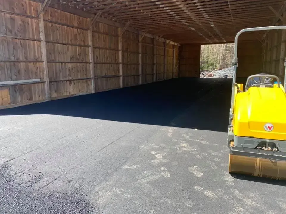 A yellow tractor is parked in front of a wooden building.