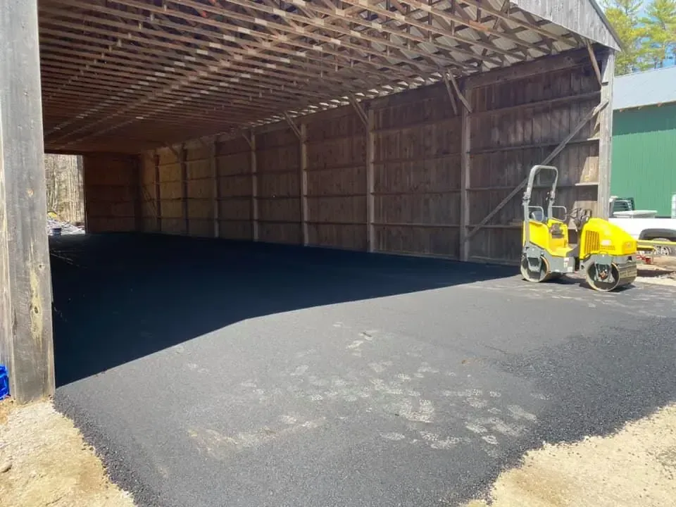 A yellow truck is parked in front of a large barn.