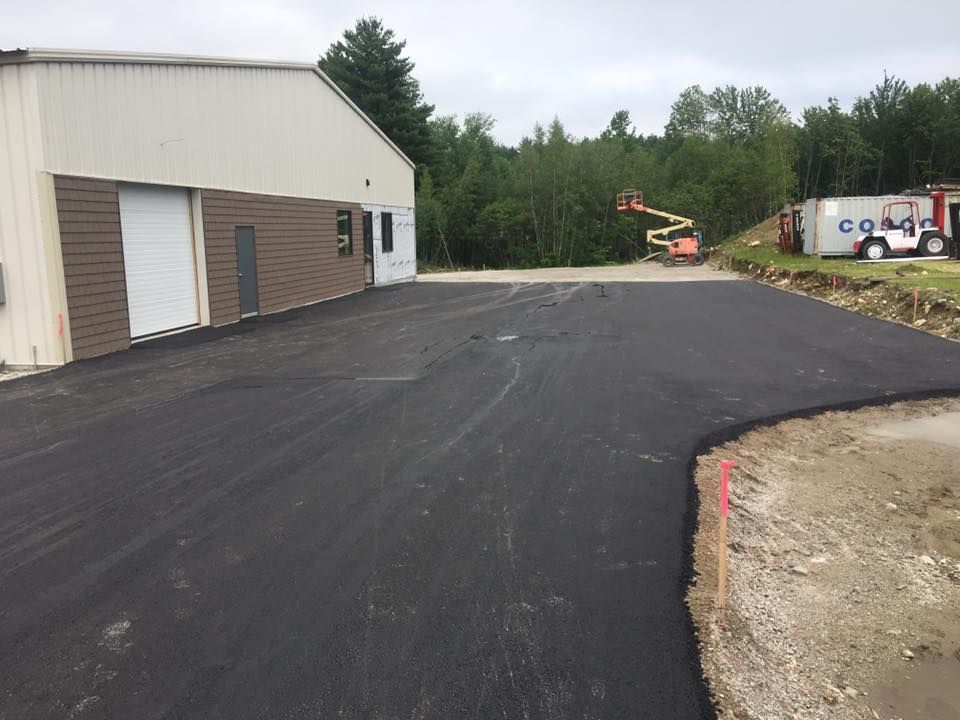 A asphalt driveway is being built in front of a building.