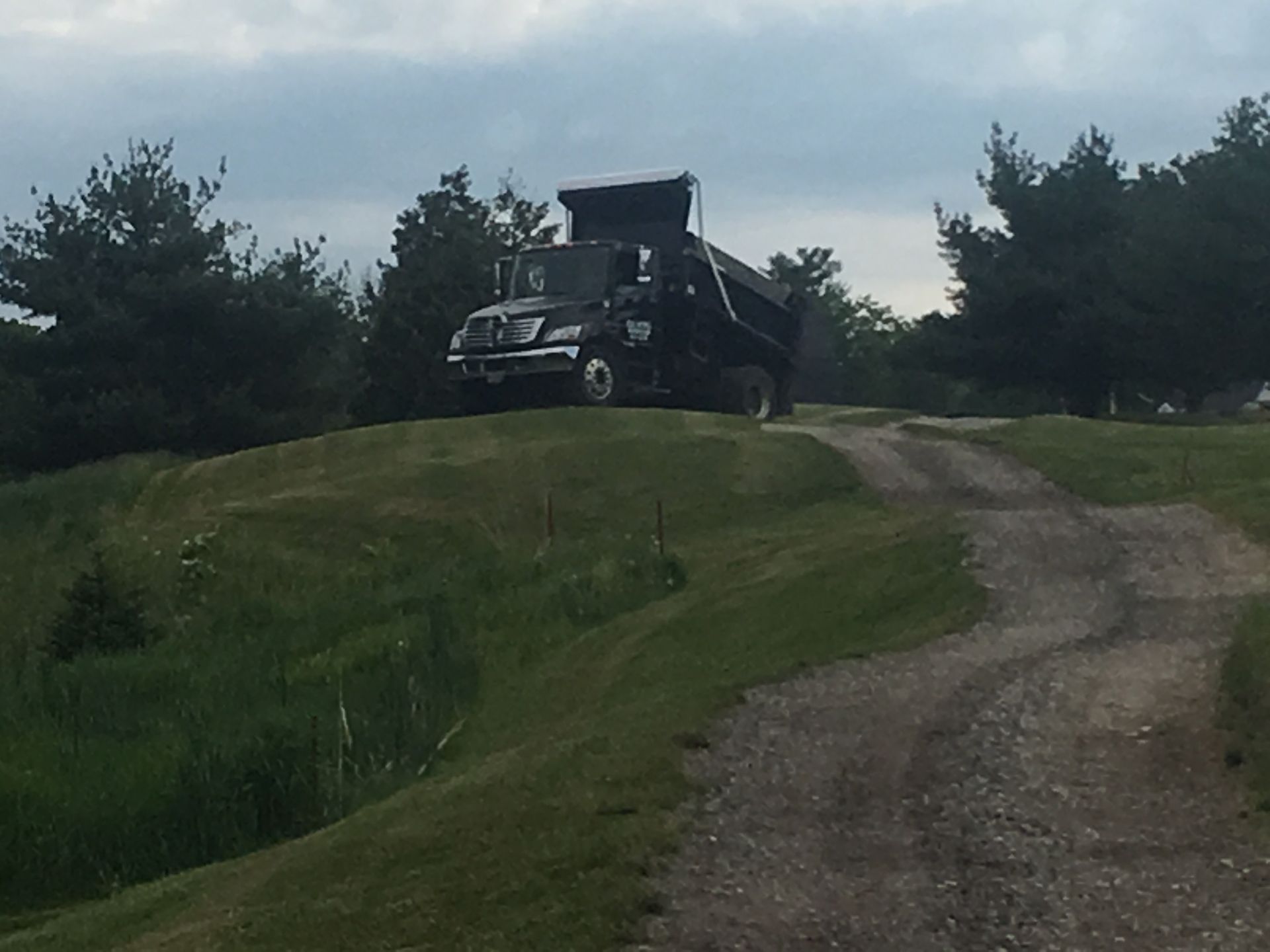 A dump truck is driving down a dirt road