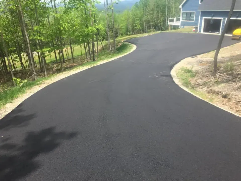 A curvy driveway leading to a house on a hill.