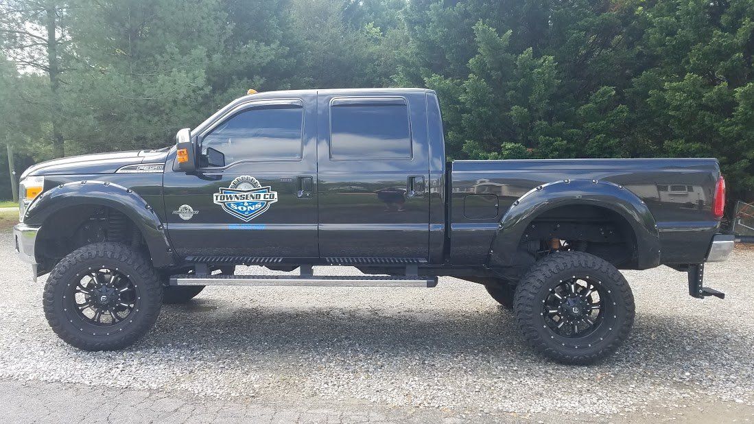 A black pickup truck is parked in a gravel lot.