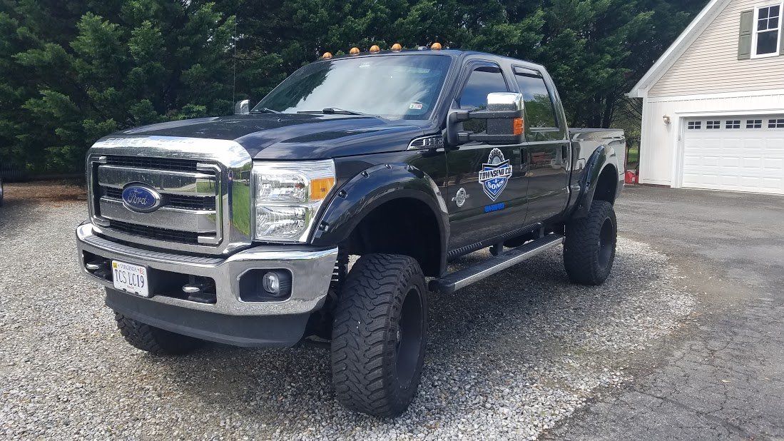A black ford truck is parked in front of a garage.