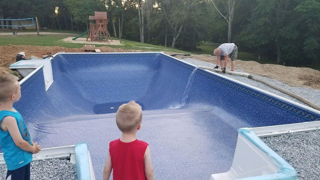 Two young boys are standing in front of a swimming pool being built.