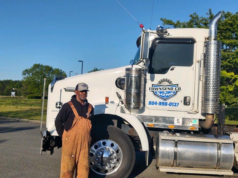 A man in overalls is standing in front of a semi truck.