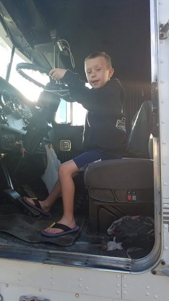 A young boy is sitting in the driver 's seat of a semi truck.