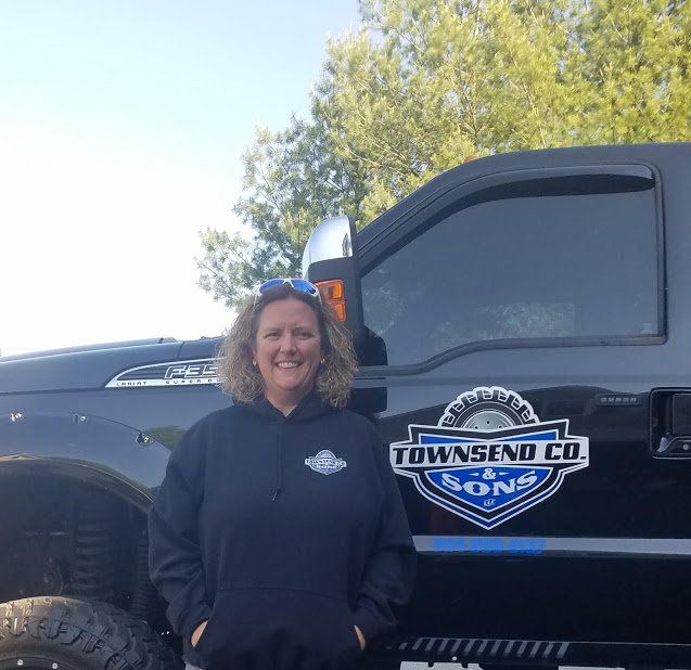 A woman is standing in front of a truck that says townsend co