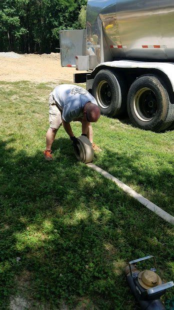 A man is kneeling down in the grass next to a truck.