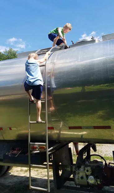 Two children are climbing up the side of a tanker truck