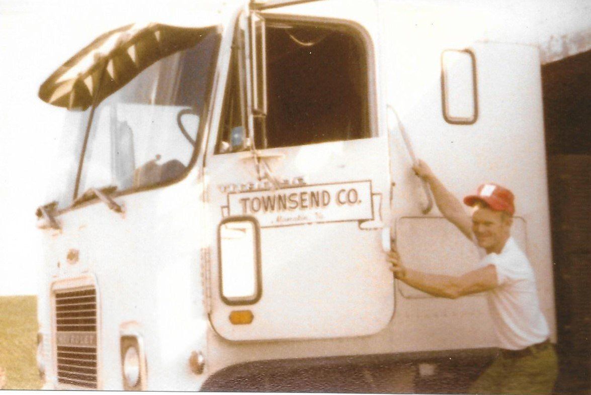 A man is opening the door of a white townsend co. truck