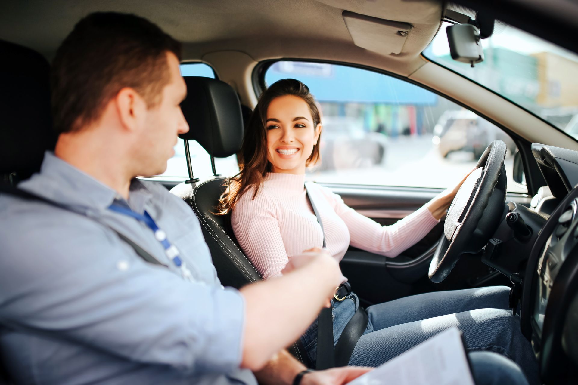 Driving instructor teaching student how to drive in a car, hands on steering wheel. Driving instructor teaching student how to drive in a car, hands on steering wheel.