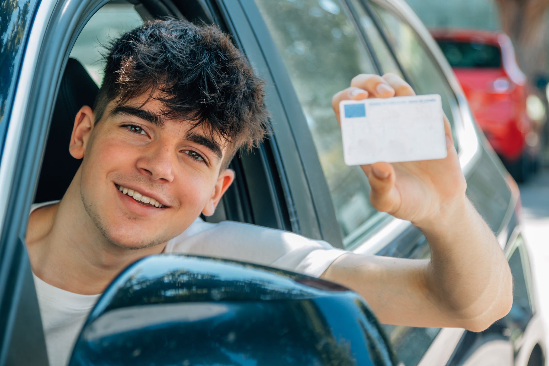Young driver showing his official license after completing lessons.