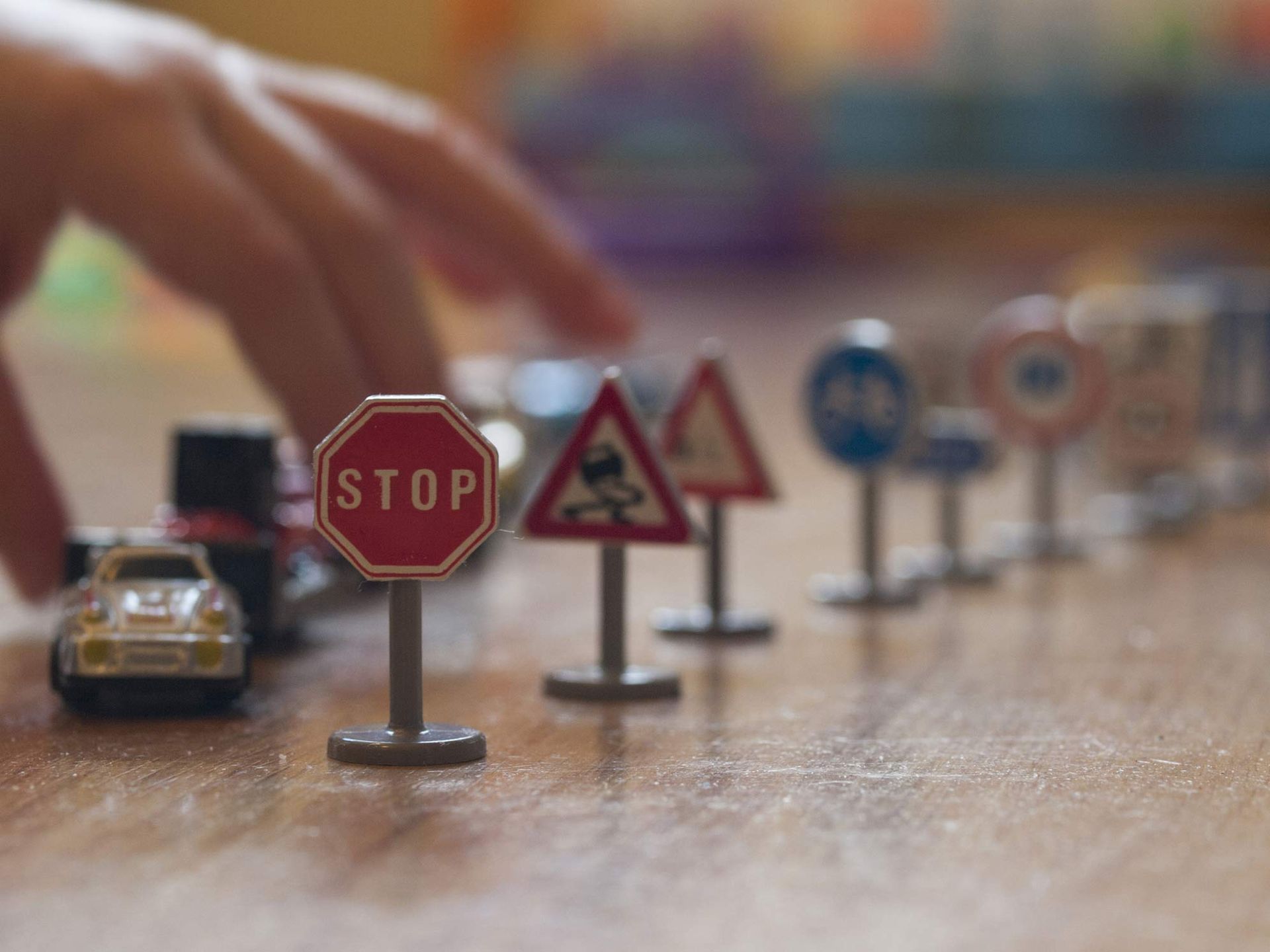 Toy cars and traffic signals on wooden floor.
