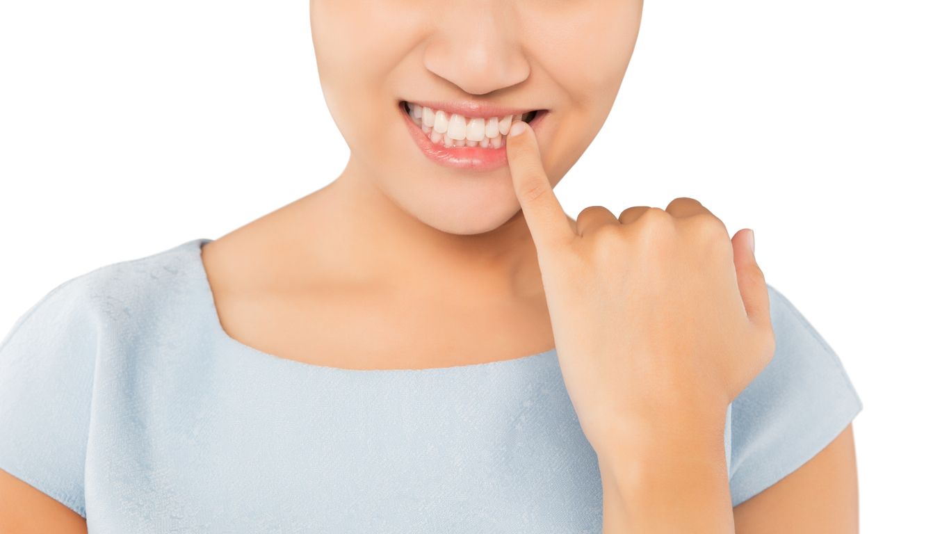 A woman is smiling and holding her finger to her mouth.