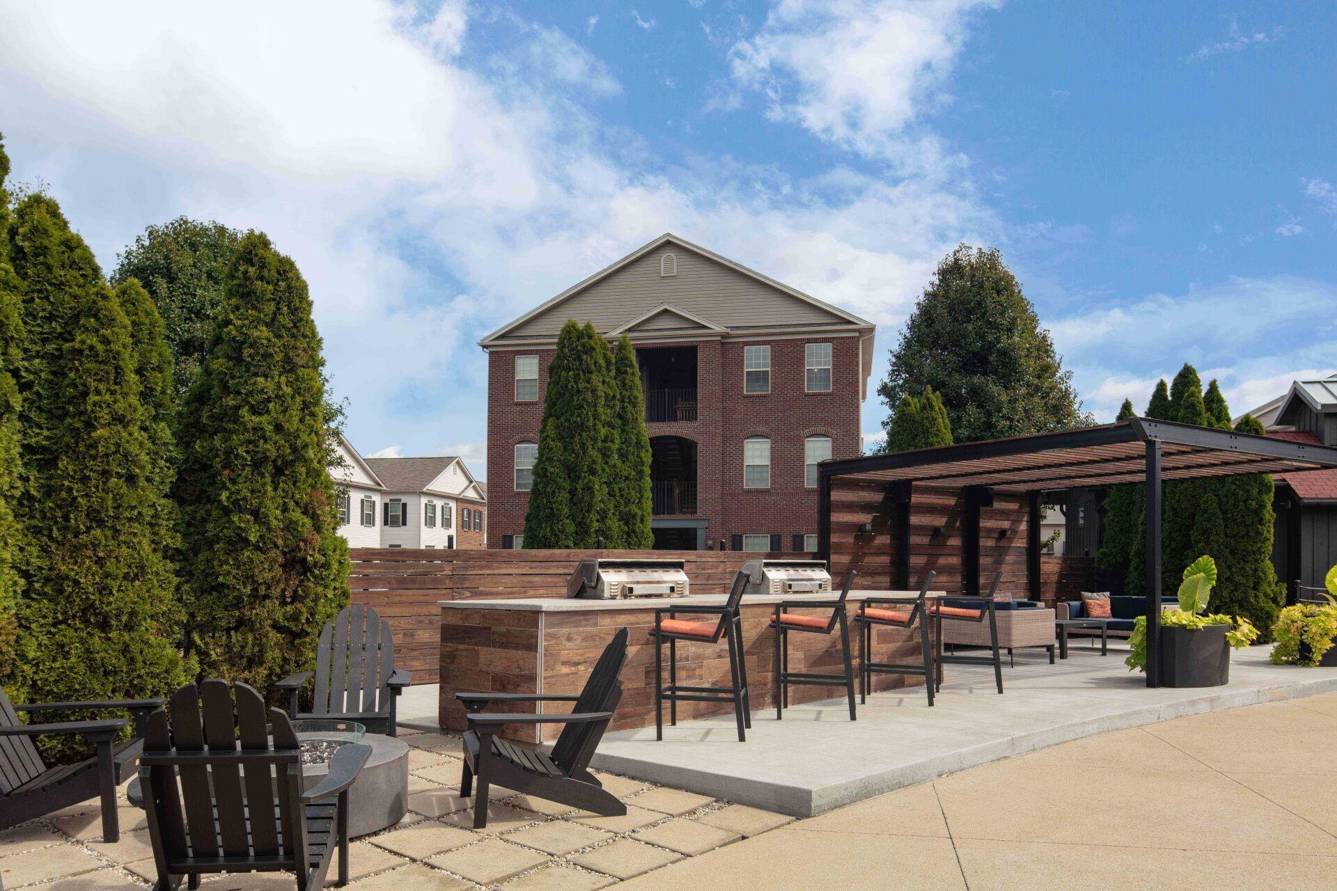 A patio area with chairs and a grill in front of a brick building.