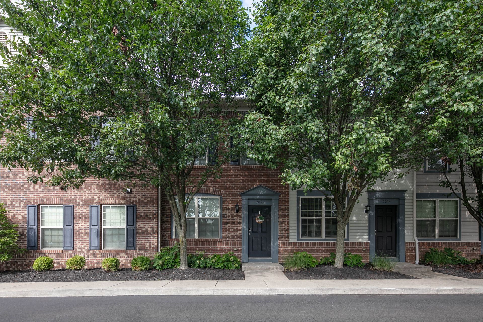 A row of brick houses with trees in front of them