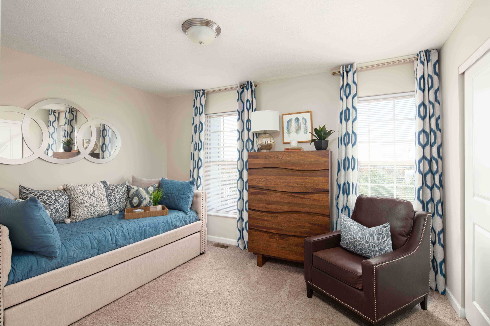 A bedroom with a day bed , chair , dresser and window.