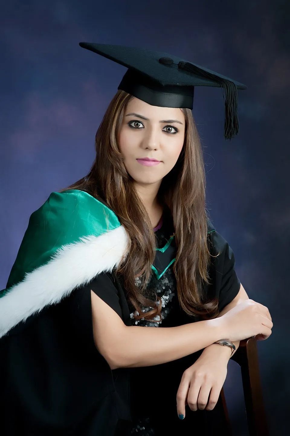 Woman in Graduation Attire with a Dark Background
