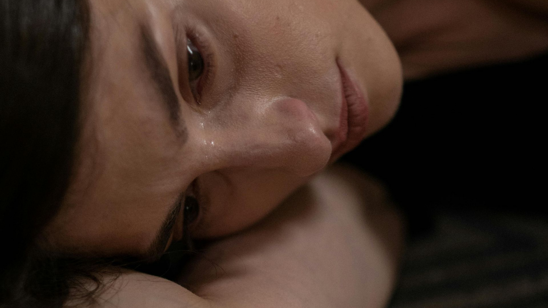 A man is hugging a woman who is crying in front of a mirror.