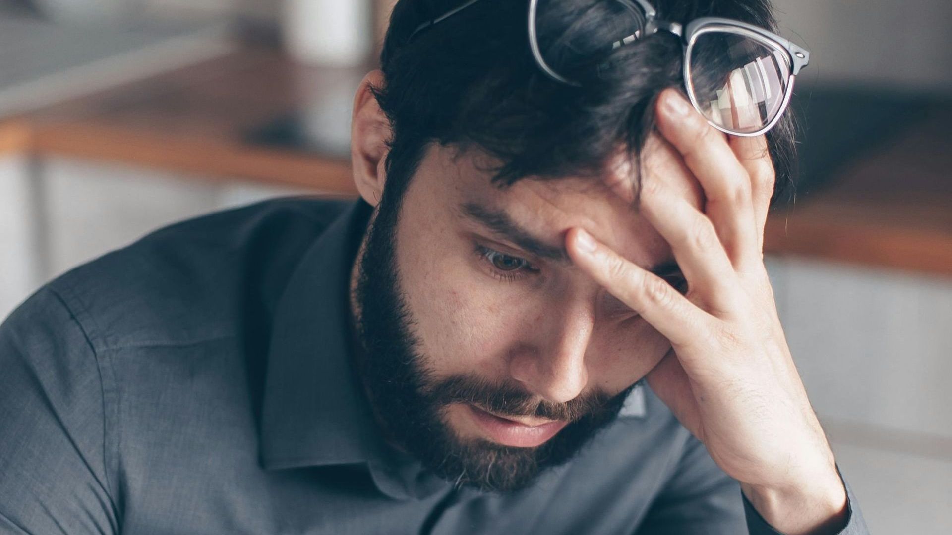 A man is hugging a woman who is crying in front of a mirror.