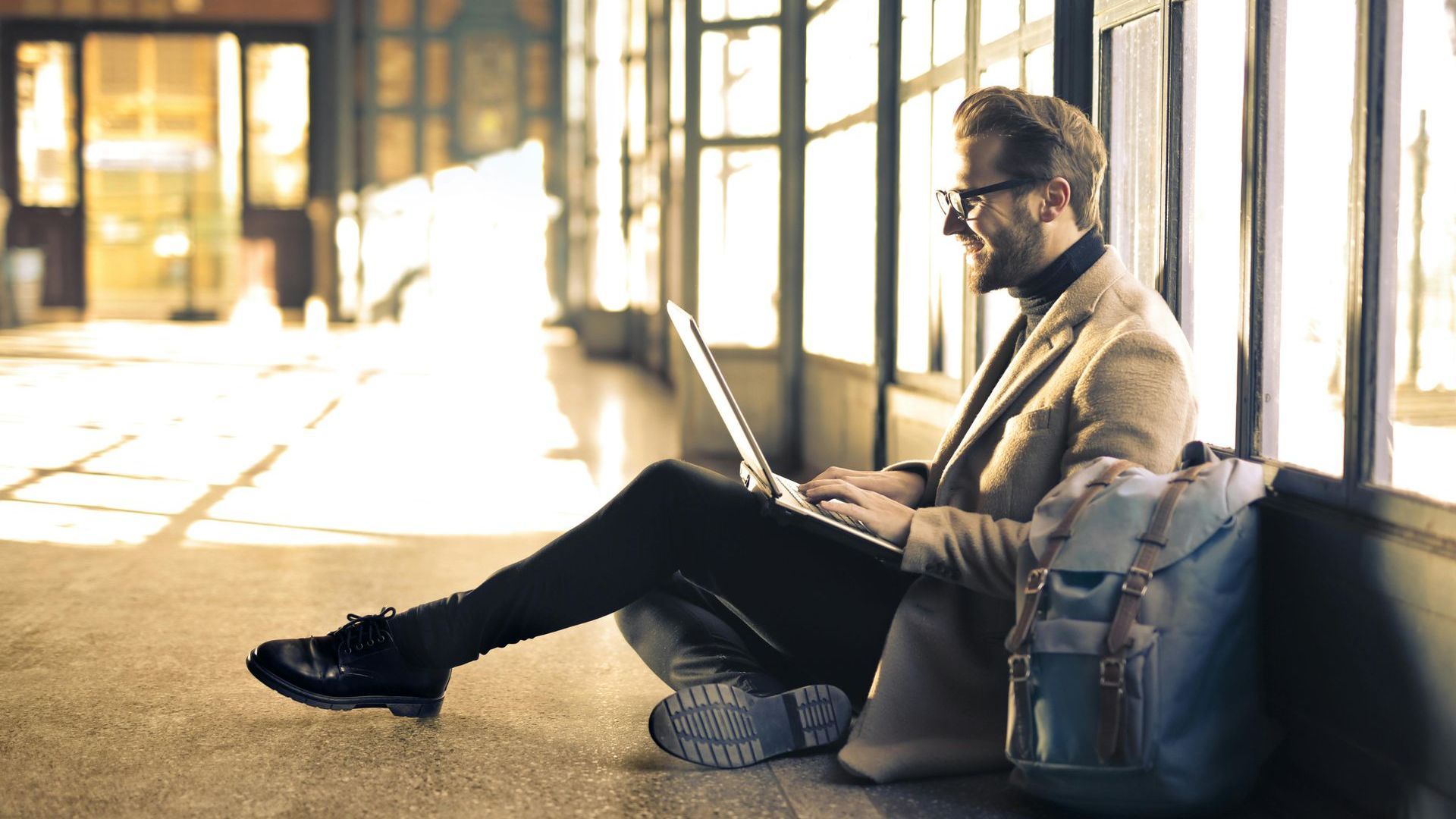 A man is sitting on the floor using a laptop computer.