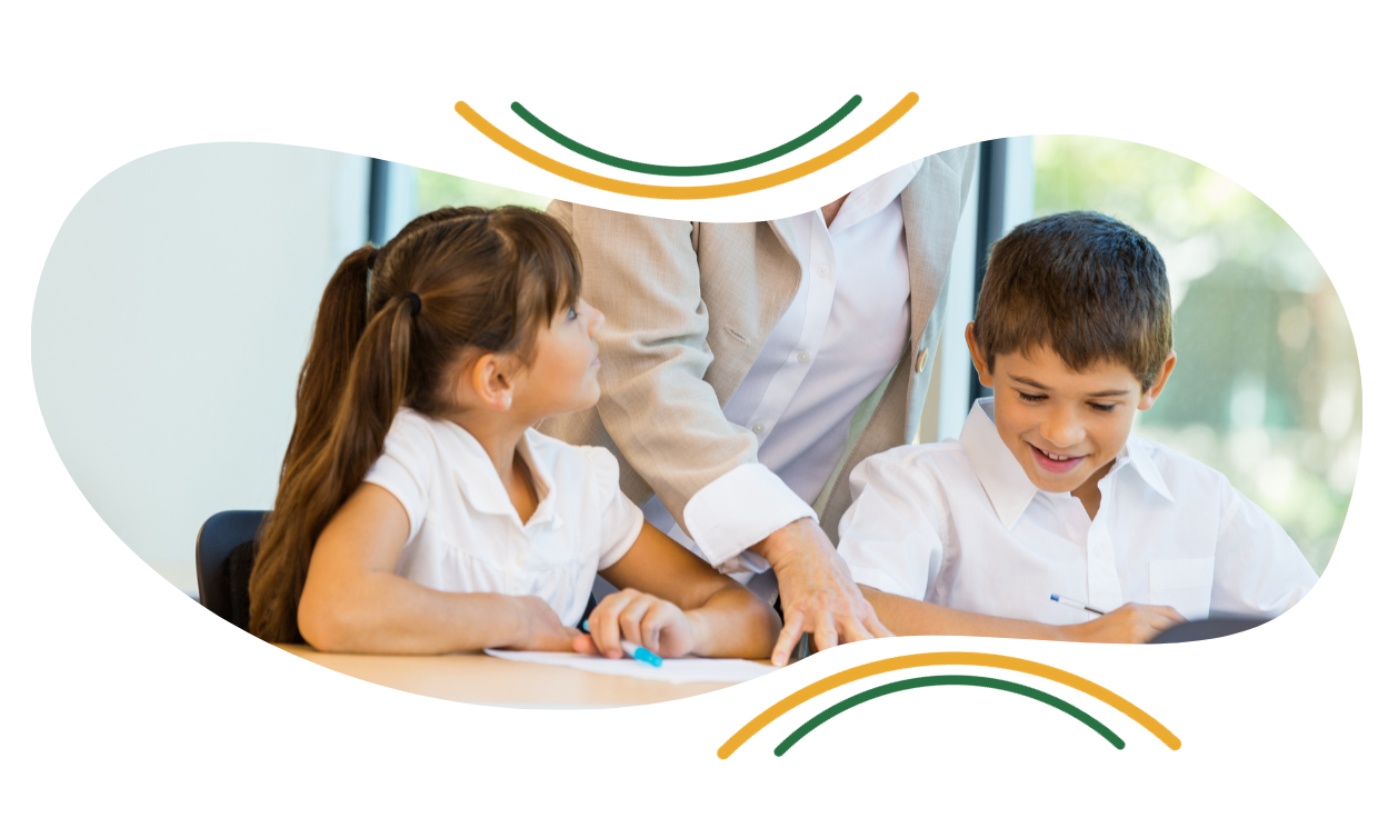 A teacher is helping two children with their homework in a classroom.