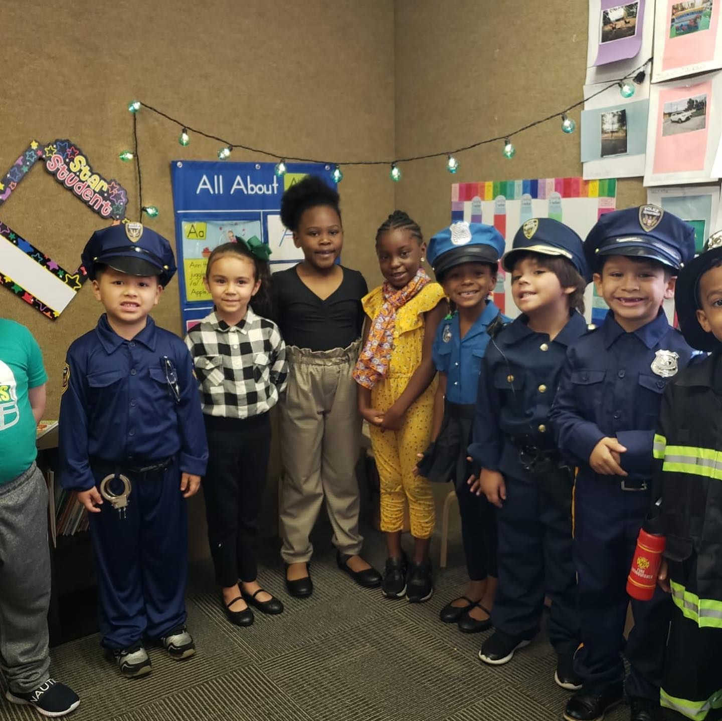 A group of children posing for a picture in front of a sign that says all about