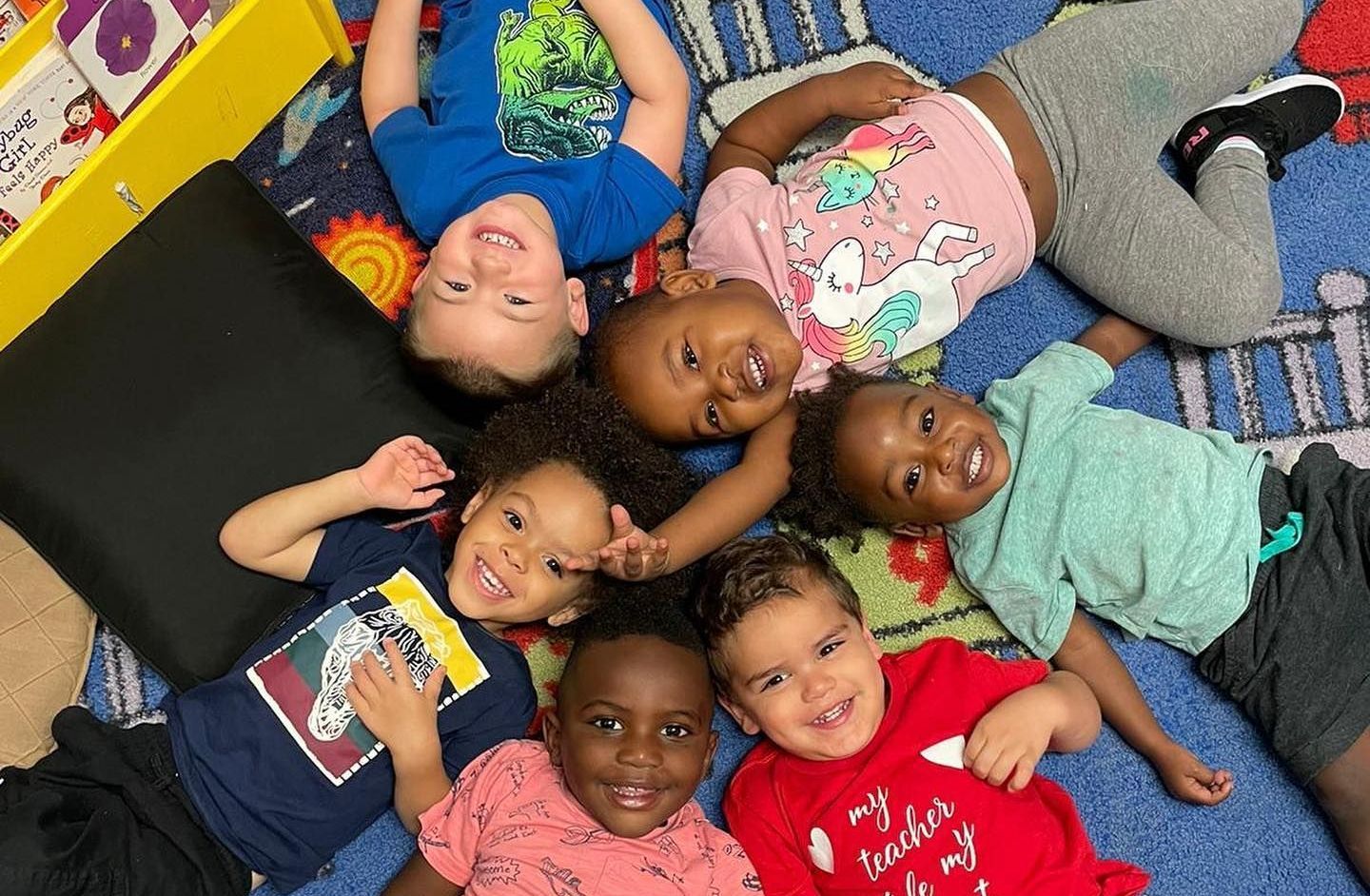 A group of children are laying on the floor in a circle.