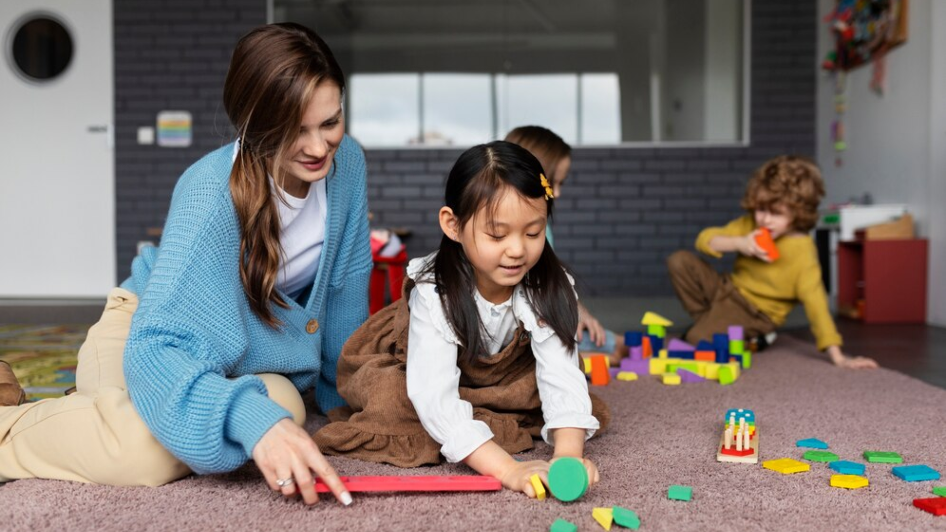 A woman and a little girl are playing with blocks on the floor.