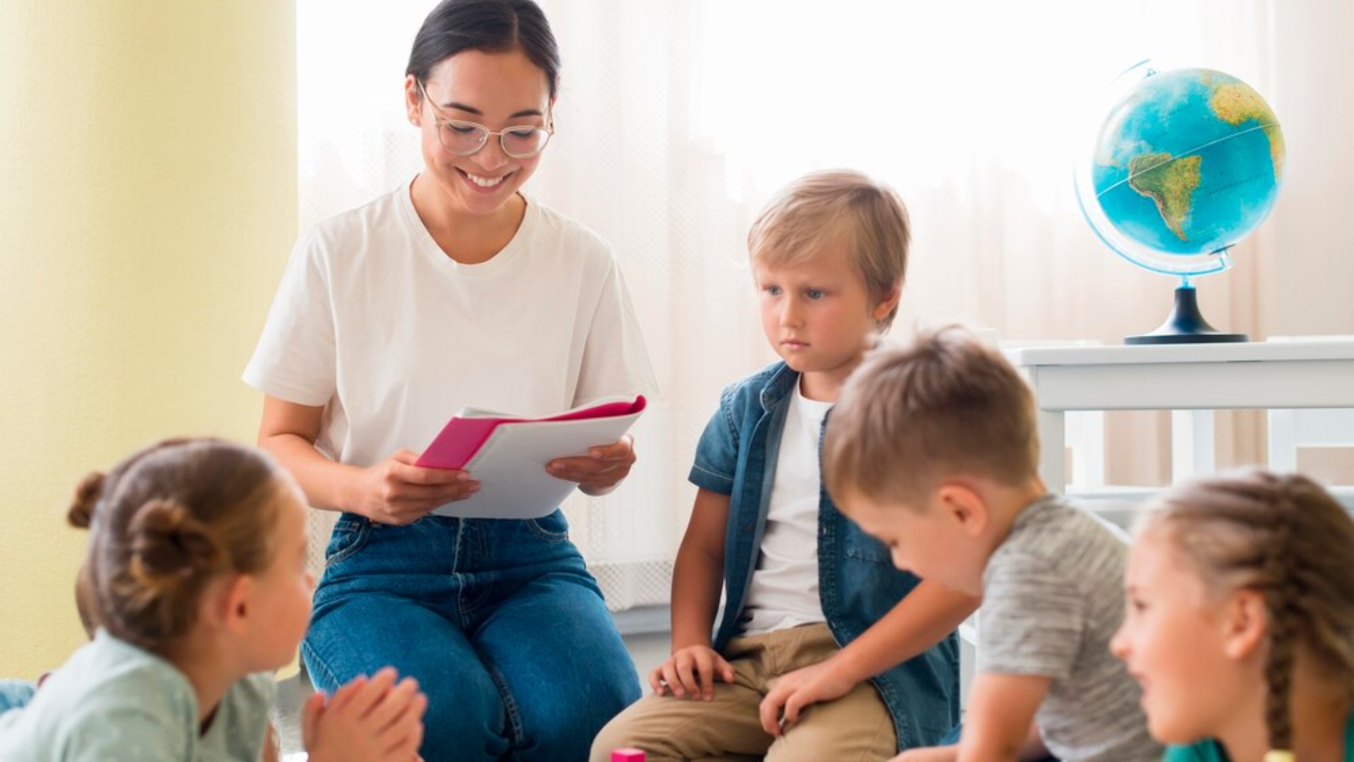 A woman is sitting on the floor reading a book to a group of children.