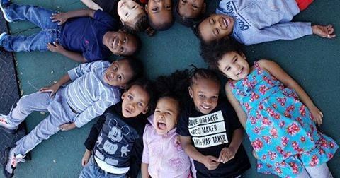 A group of children are laying in a circle on the ground.