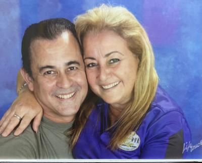 A man and a woman are posing for a picture and smiling for the camera.