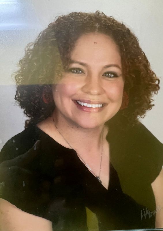 A woman with curly hair is smiling and wearing a black shirt.
