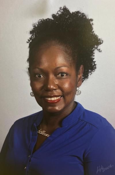 A woman in a blue shirt is smiling for the camera