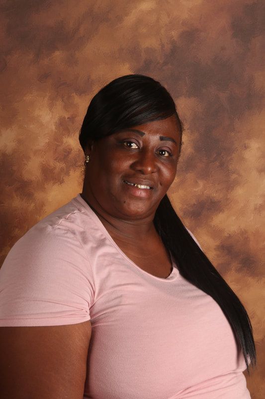 The woman is wearing a pink shirt and smiling for the camera.
