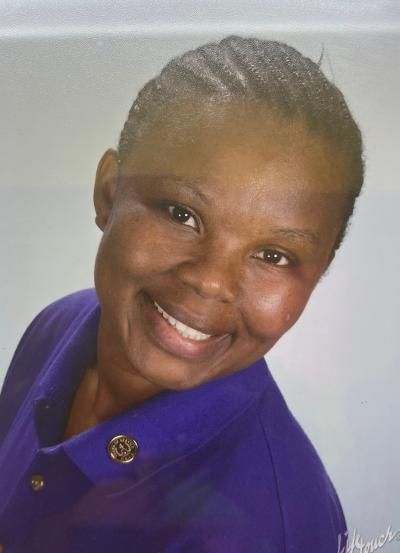 A woman in a purple shirt is smiling for the camera.