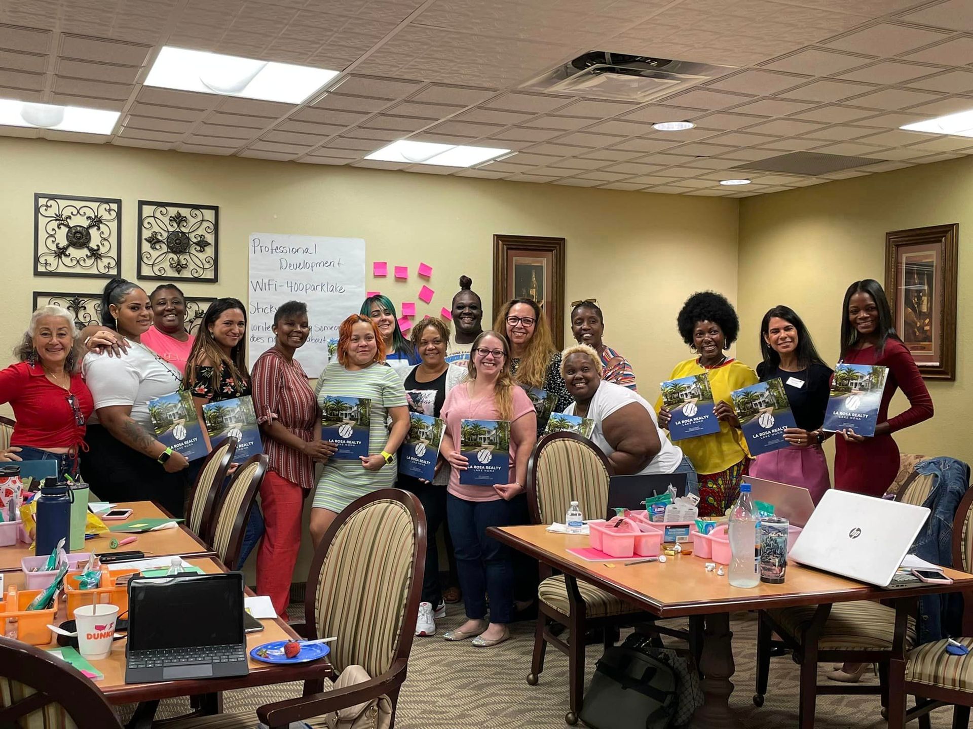 A group of people are standing around a table in a room holding books.