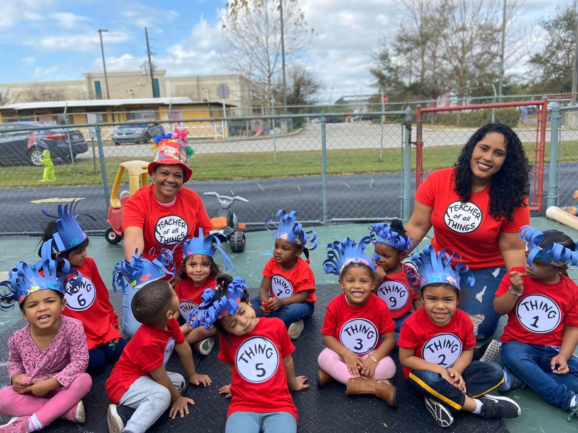 A group of children are sitting on the ground wearing hats.